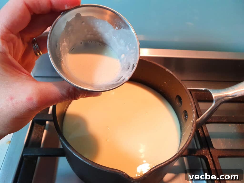 Cookies and Cream Ice Cream Recipe 10 adding milk and tapioca starch slurry to ice cream min in pot on stove.