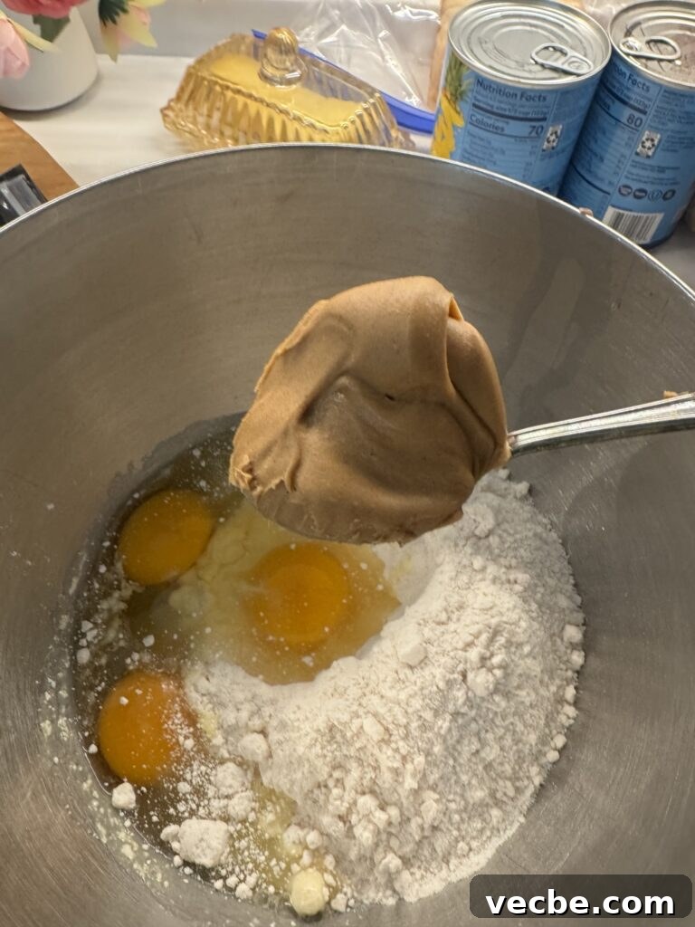Vanilla Cake with Creamy Peanut Butter Frosting 3 A big spoon of peanut butter over eggs and cake mix in a bowl
