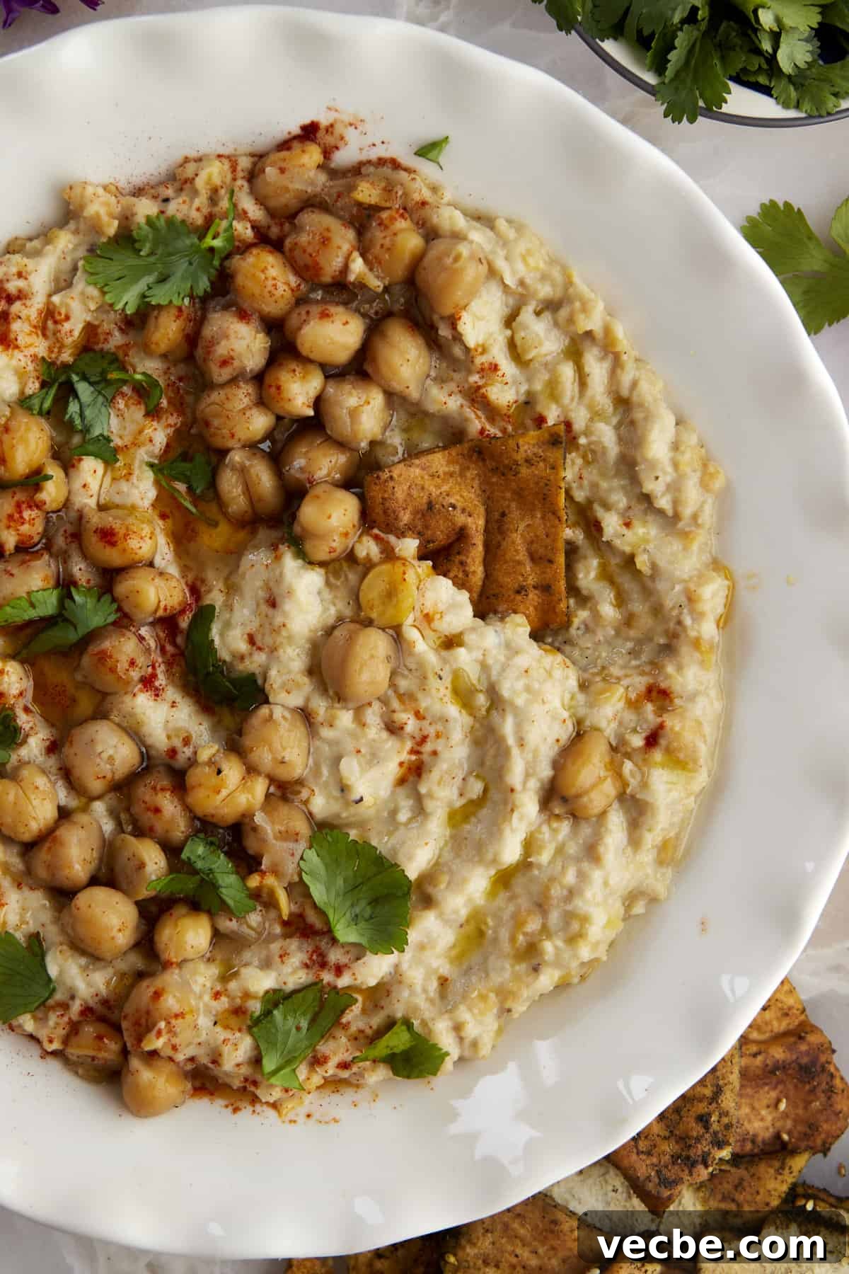 How to Make Chunky Garlic Hummus (Masabaha) 4 Pita chip dipping into chunky garlic hummus (masabaha)