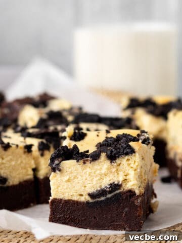 Oreo cheesecake brownies sliced into squares with a glass of milk in the background