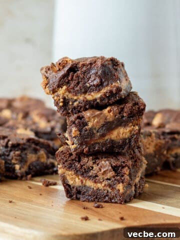 Stack of chocolate peanut butter cup brownies on a wood cutting board