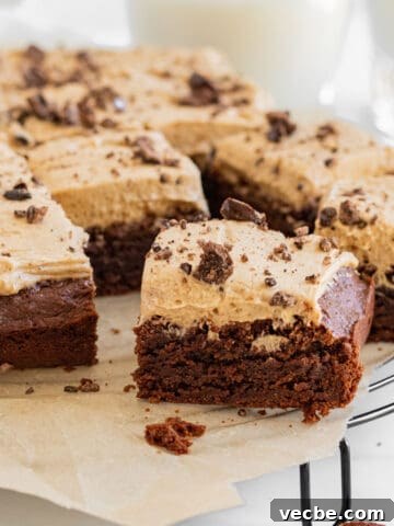 Brownies with espresso frosting on a cooling rack with glasses of milk in the background