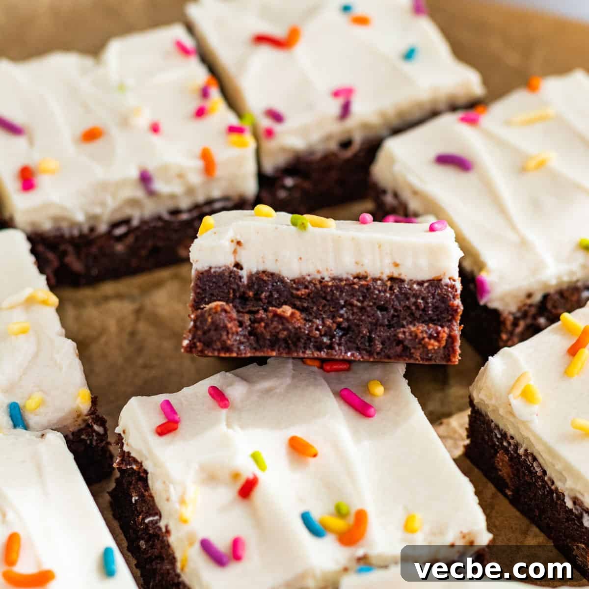 Chewy Brownies with Cream Cheese Frosting Recipe 9 Sliced brownies with cream cheese frosting and colored sprinkles on parchment paper