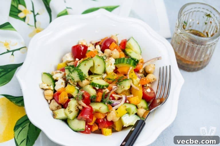 Overhead view of a bowl of Mediterranean Chickpea Salad with Lemon-Herb Vinaigrette with dressing on the side