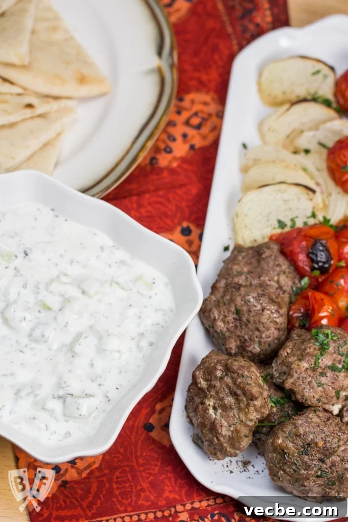 Overhead view of a Persian meal with yogurt, kebab, veggies, and pita.