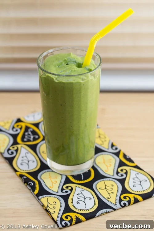 Green smoothie in a glass with a yellow straw.
