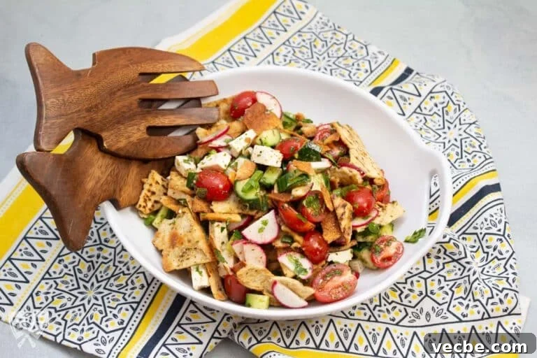 Bowl of fattoush salad with serving utensils.