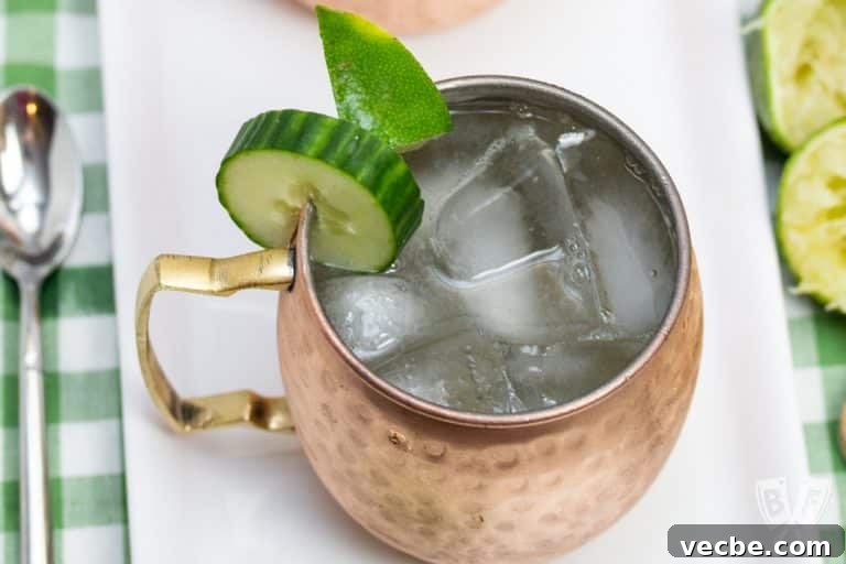 Overhead view of a copper mug filled with a Cucumber Moscow Mule cocktail with ingredients alongside.