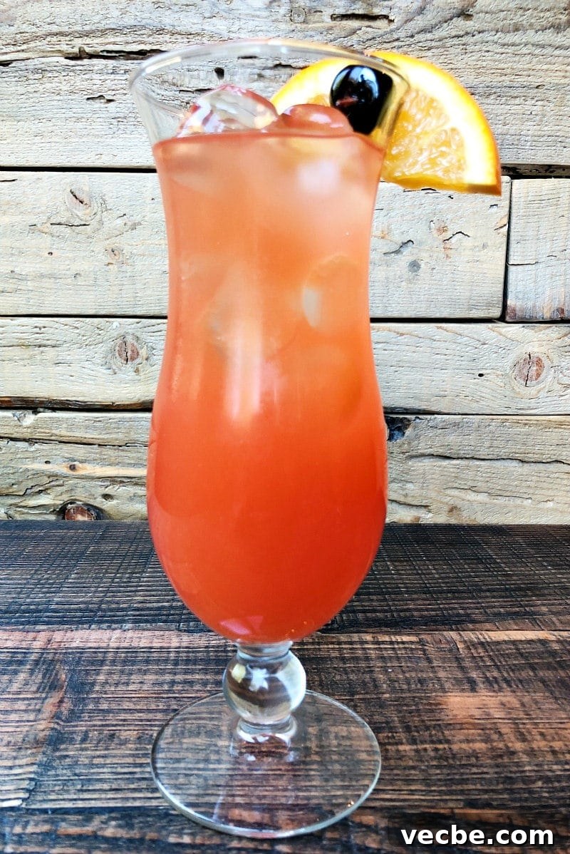 Hurricane Cocktail Recipe hurricane cocktail in a hurricane glass with a wooden background