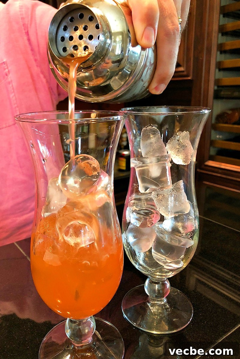Pouring Hurricane Cocktails man in a pink shirt pouring hurricane cocktails into hurricane glasses