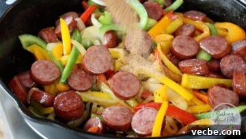 Authentic Cajun Sausage and Peppers Recipe 8 Adding the Cajun seasoning to the sausage and peppers in a skillet
