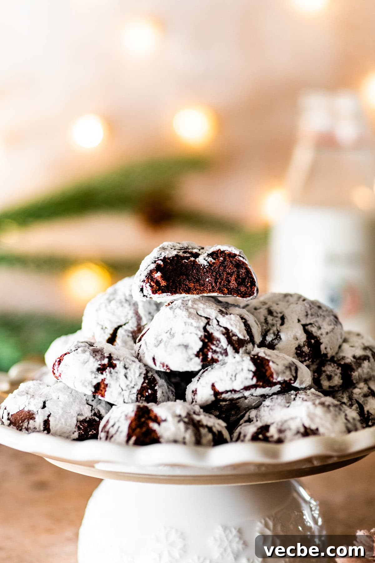 65+ Christmas Dessert Recipes Your Guests Will Love 16 Chocolate Crinkle Cookies on a platter ready to serve with Christmas lights in the background.