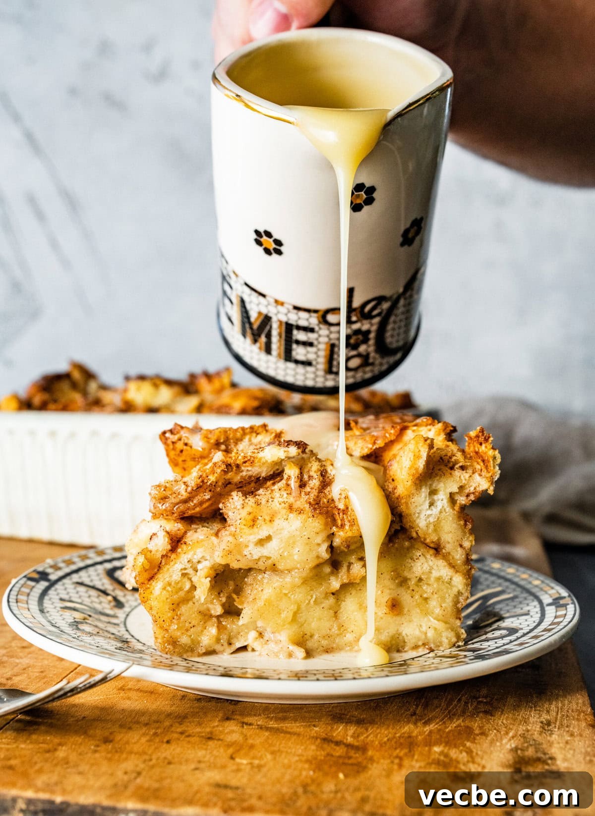 65+ Christmas Dessert Recipes Your Guests Will Love 22 Pouring the warm vanilla sauce over the top of a bread pudding slice.