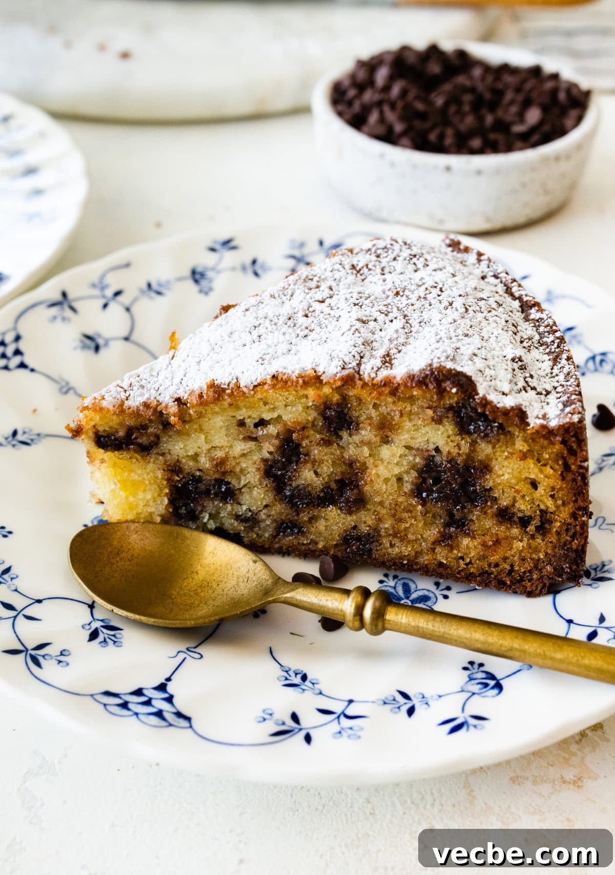 65+ Christmas Dessert Recipes Your Guests Will Love 27 One slice of chocolate chip ricotta cake on a white plate with blue flowers on it. Gold spoon on the plate.