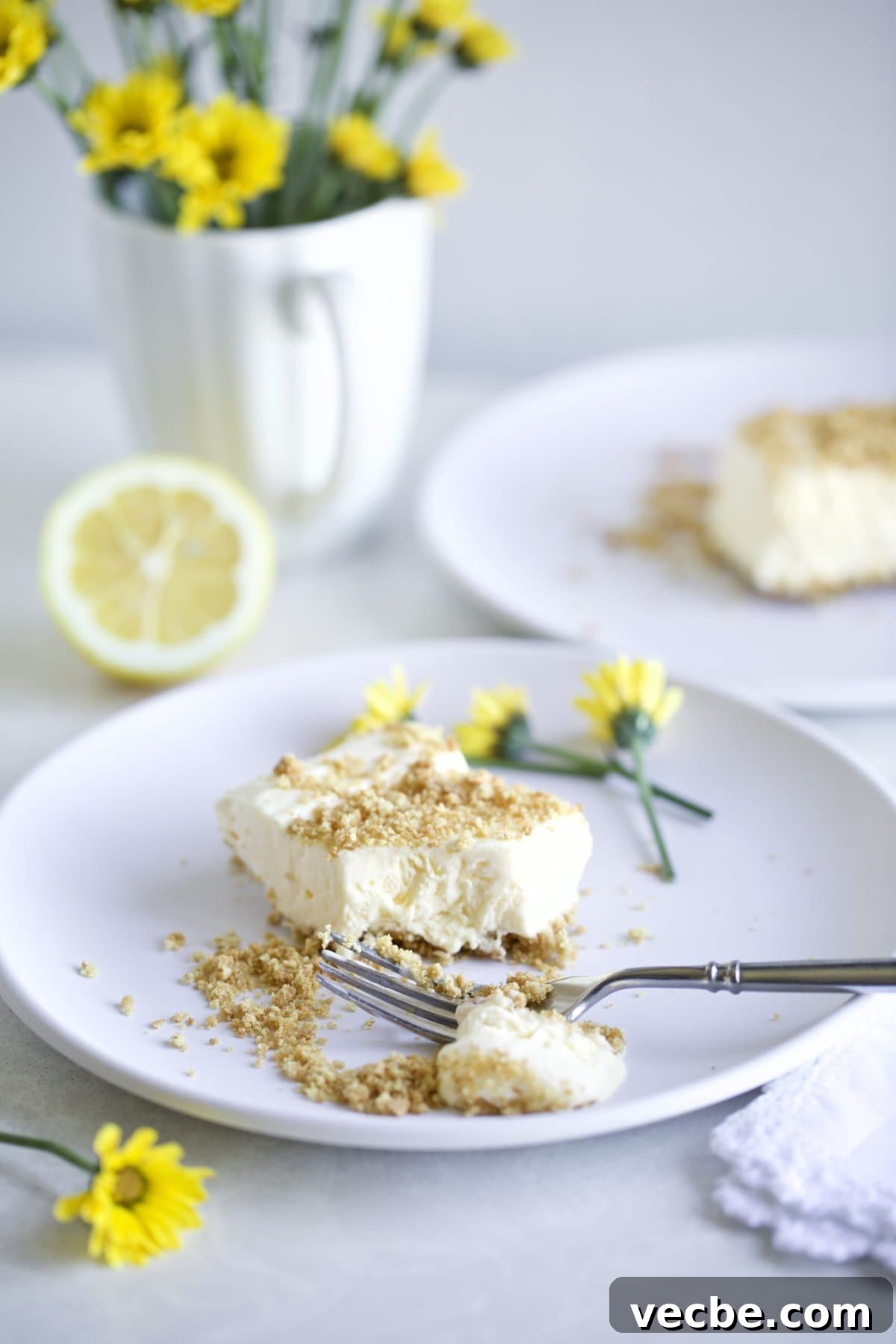 65+ Christmas Dessert Recipes Your Guests Will Love 32 Creamy Frozen Lemon dessert with graham cracker crust on a plate with yellow flowers