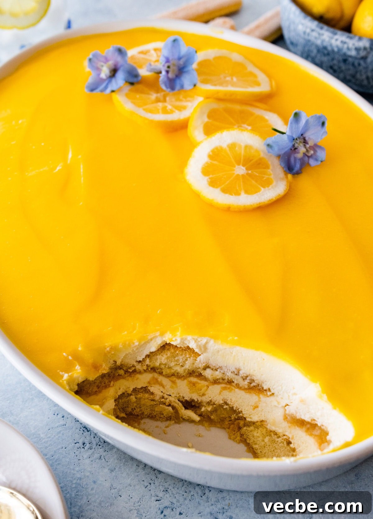65+ Christmas Dessert Recipes Your Guests Will Love 33 Lemon Tiramisu with lemon curd in a service dish with a scoop missing.