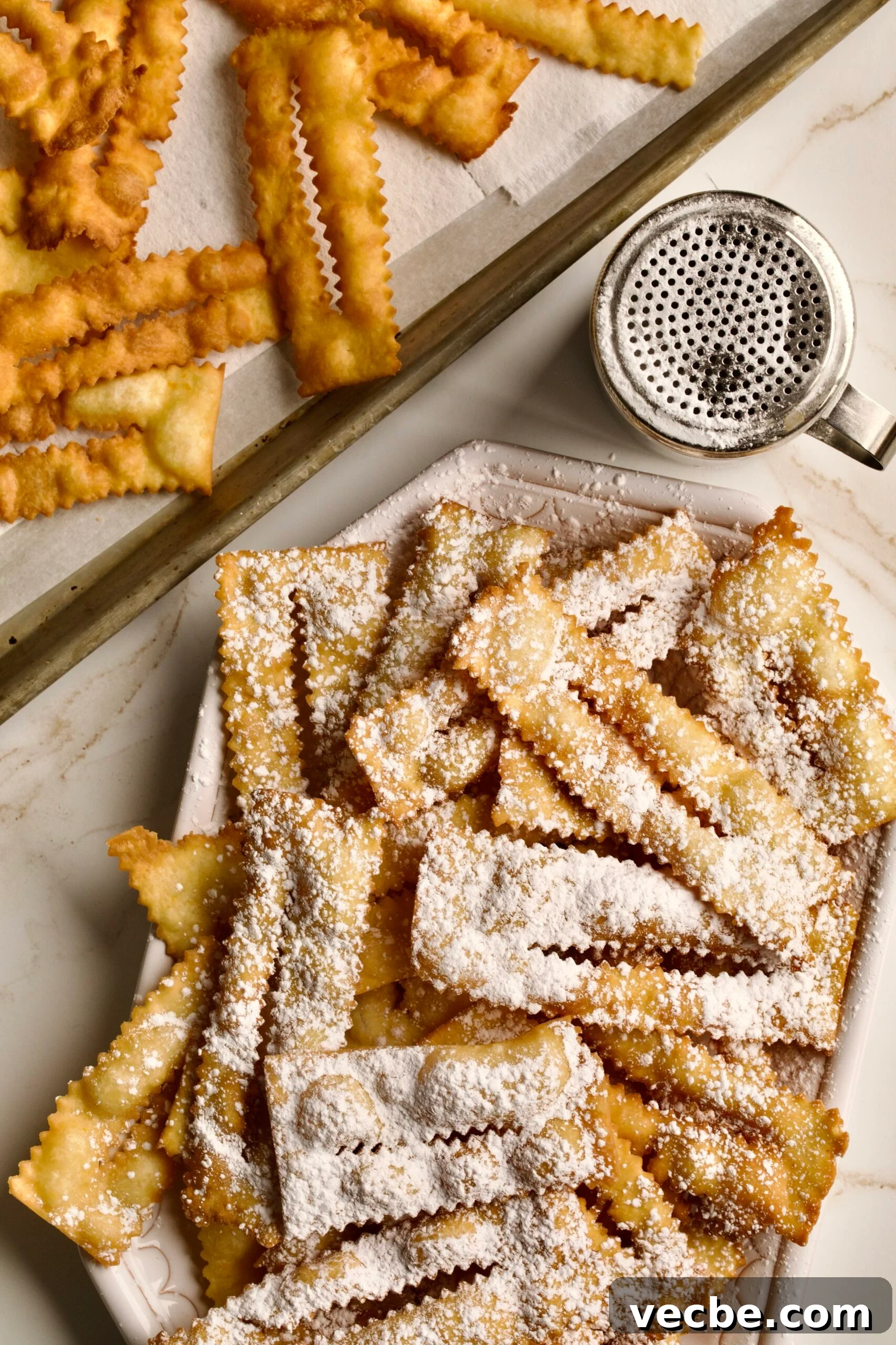 65+ Christmas Dessert Recipes Your Guests Will Love 36 final fried chiacchiere do carnivale with powdered sugar on a serving platter. with podered sugar shaker in the background.