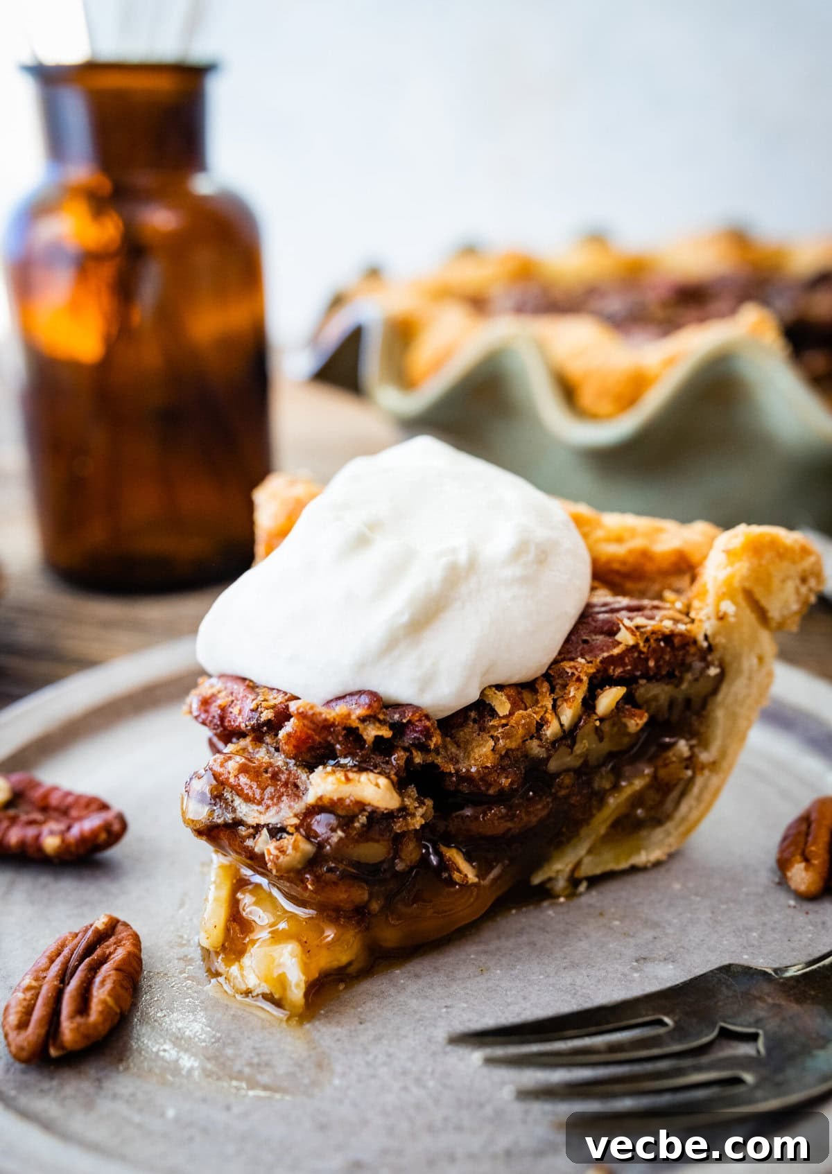 65+ Christmas Dessert Recipes Your Guests Will Love 39 Slice of baked Maple Pecan Pie on a white plate topped with a dollop of whipped cream.