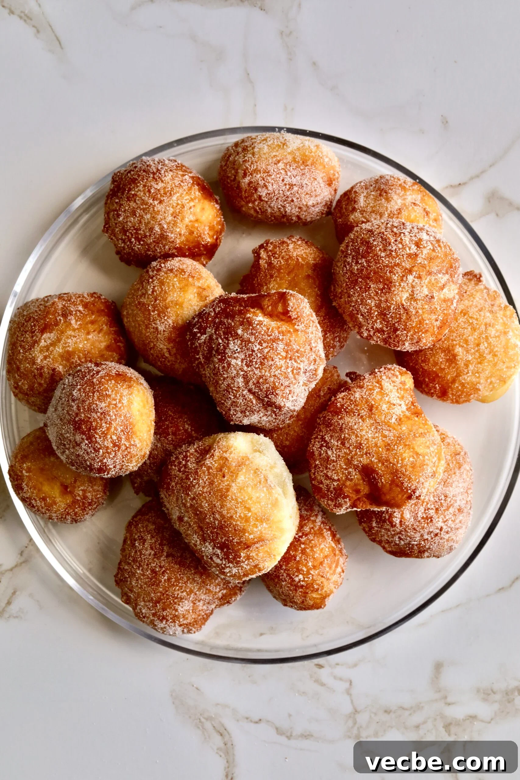 65+ Christmas Dessert Recipes Your Guests Will Love 40 zeppole on a glass serving plate.