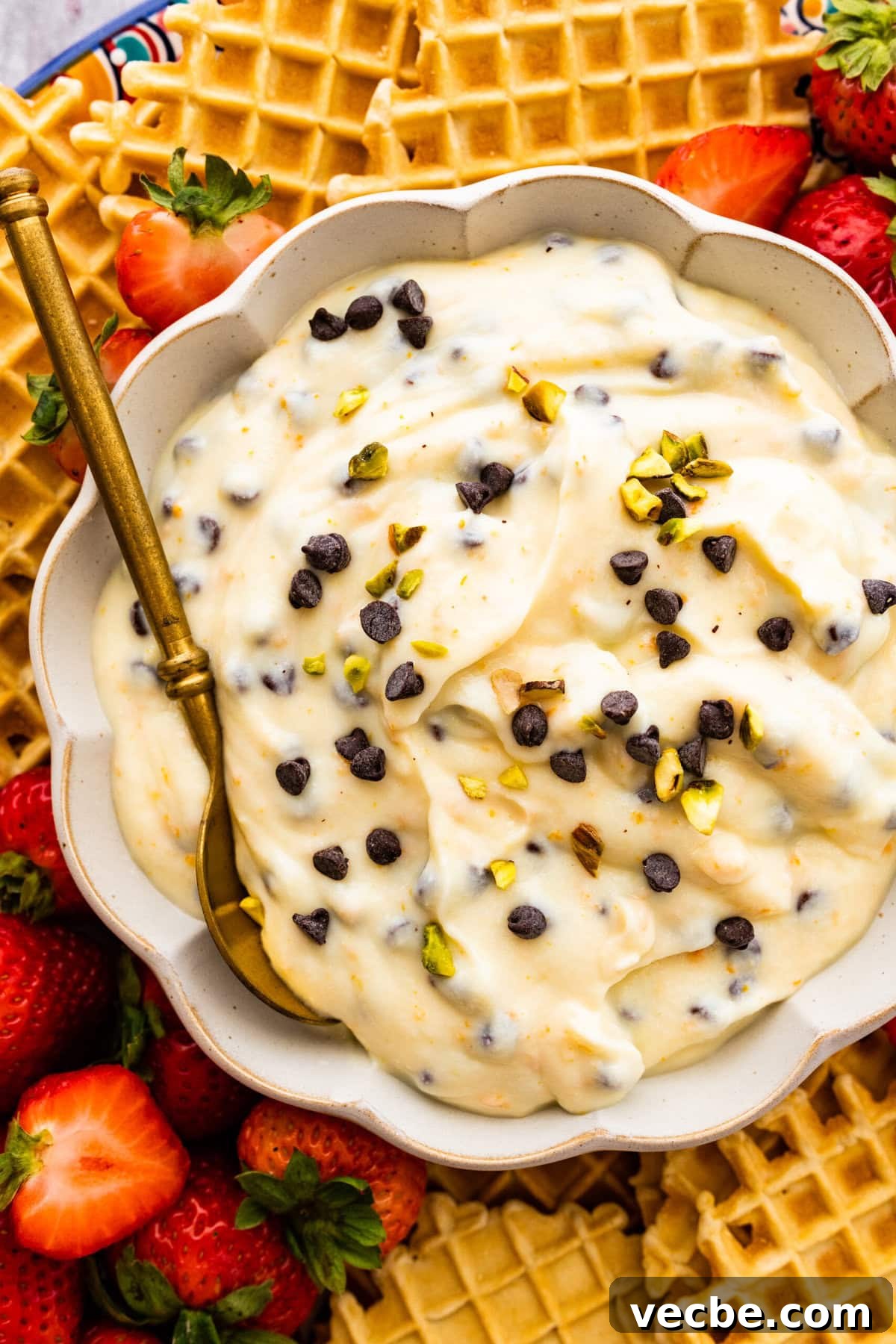 65+ Christmas Dessert Recipes Your Guests Will Love 45 Cannoli dip topped with pistachios in a bowl with a spoon.