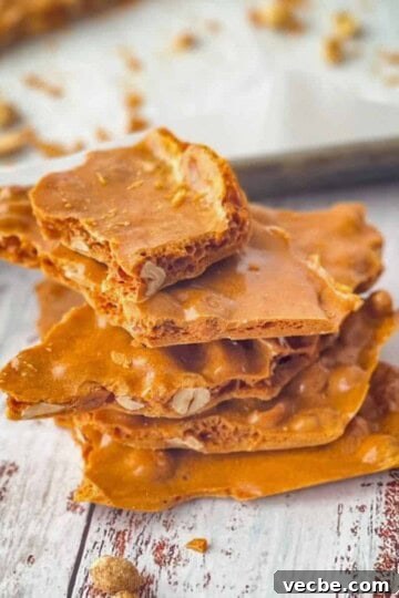 Soft peanut brittle stacked on top of each other with a pan of the rest of the brittle in the background.