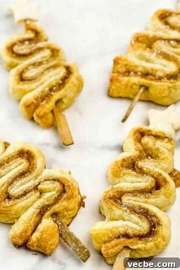 Cinnamon sugar puff pastry christmas trees on a white countertop, topped with small star sugar cookies.