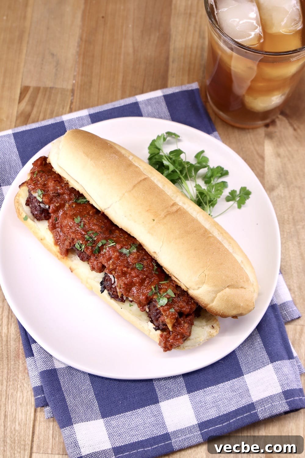 Meatball Subs are a crowd favorite sandwich recipe. plate with meatball sub with marinara, glass of tea