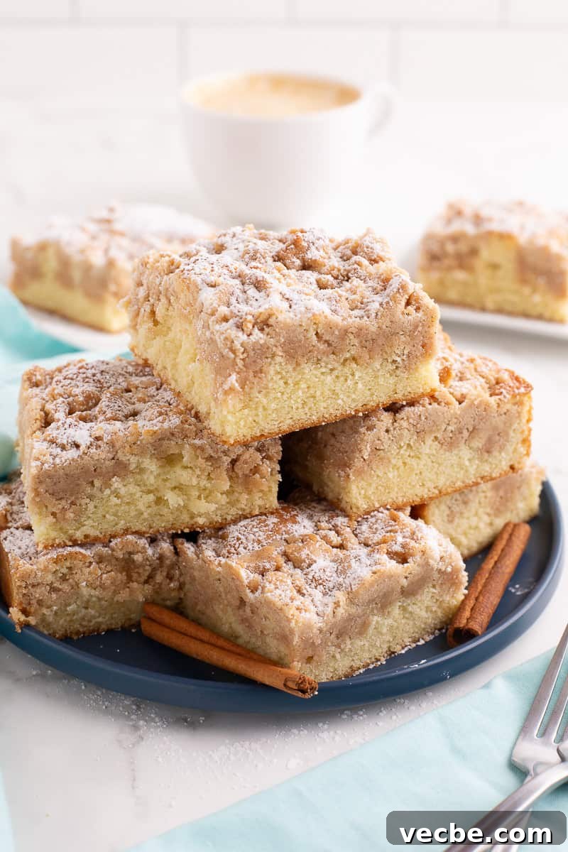Crumb Cake Recipe with Cinnamon Streusel Topping 7 Several pieces of crumb cake stacked on a blue plate.