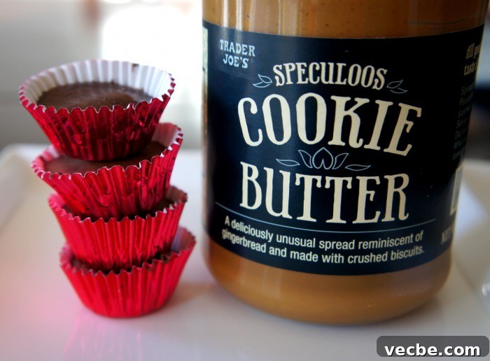 Chocolate Cookie Butter Cups - cookie butter filled chocolate candies! Four chocolates in red wrappers stacked on top of each other next to a jar of cookie butter