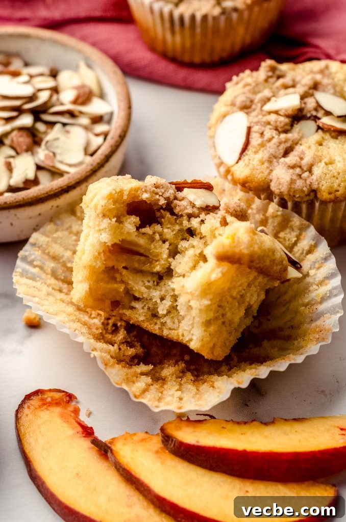 Peach Almond Streusel Muffins with Crumb Topping 13 A photo of a peach almond streusel muffin with a bite taken out of it.
