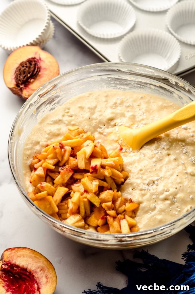 Peach Almond Streusel Muffins with Crumb Topping 9 Peach muffin batter in a large bowl with a spatula.