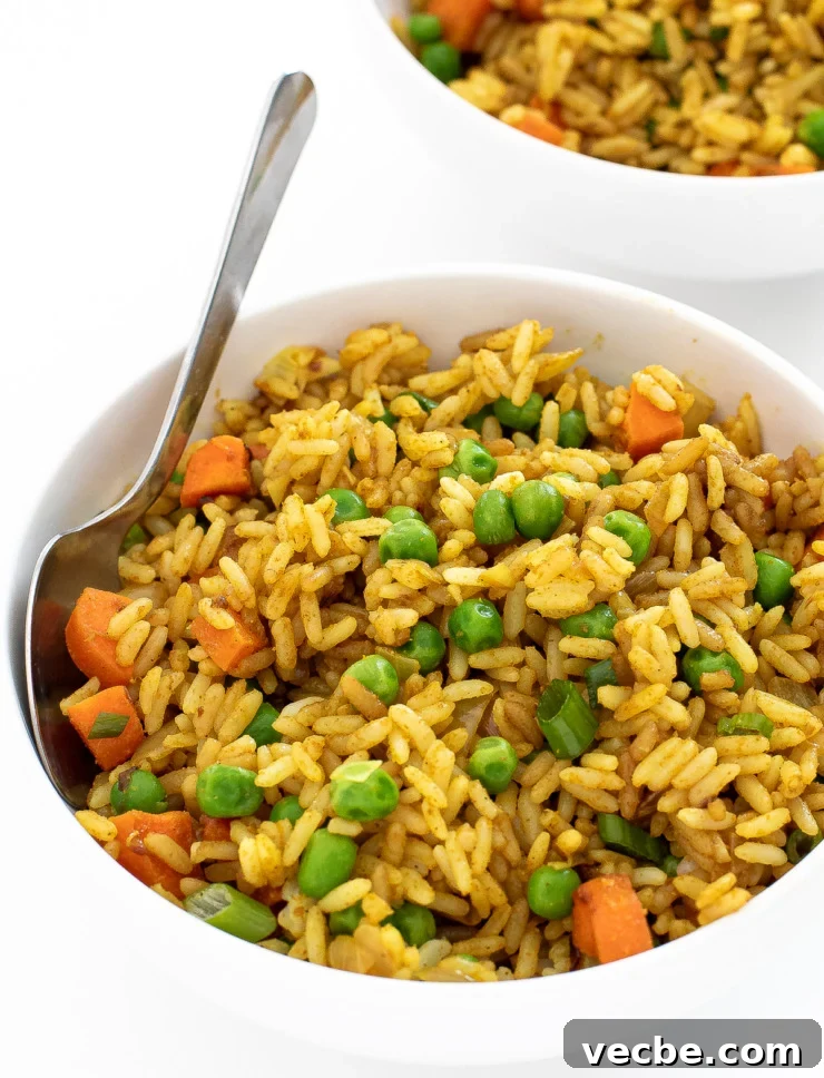 Fragrant Curry Fried Rice Recipe 9 Two bowls of curry fried rice with a silver spoon.