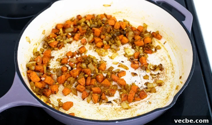 Fragrant Curry Fried Rice Recipe 4 Carrots and onions being sautéed in a skillet.