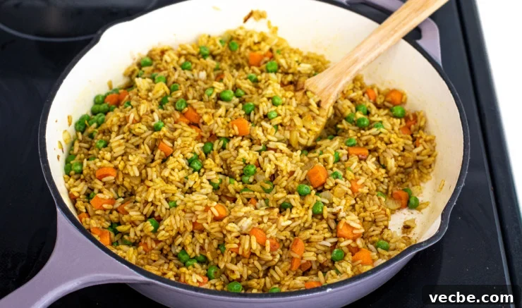 Fragrant Curry Fried Rice Recipe 5 Curry fried rice being cooked on the stove in a skillet.