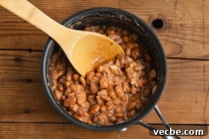 Crispy Baked Bean and Cheese Tacos with Avocado Crema 15 This is a picture of the pinto beans being smashed in a pot.