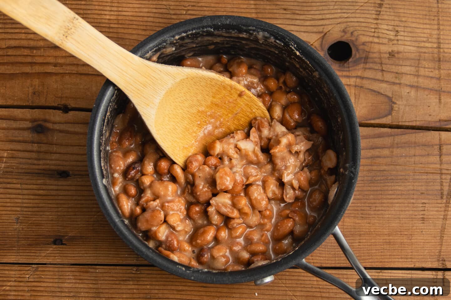Crispy Baked Bean and Cheese Tacos with Avocado Crema 8 This is a picture of the pinto beans being smashed in a pot.