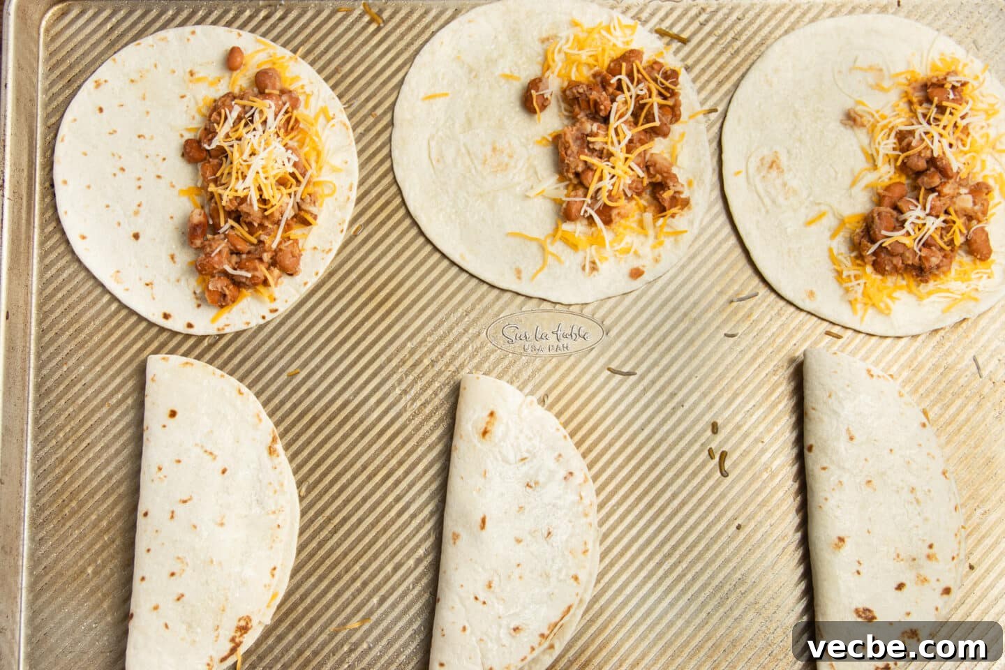 Crispy Baked Bean and Cheese Tacos with Avocado Crema 10 This is a picture of the tortillas being filled with bean and cheese.