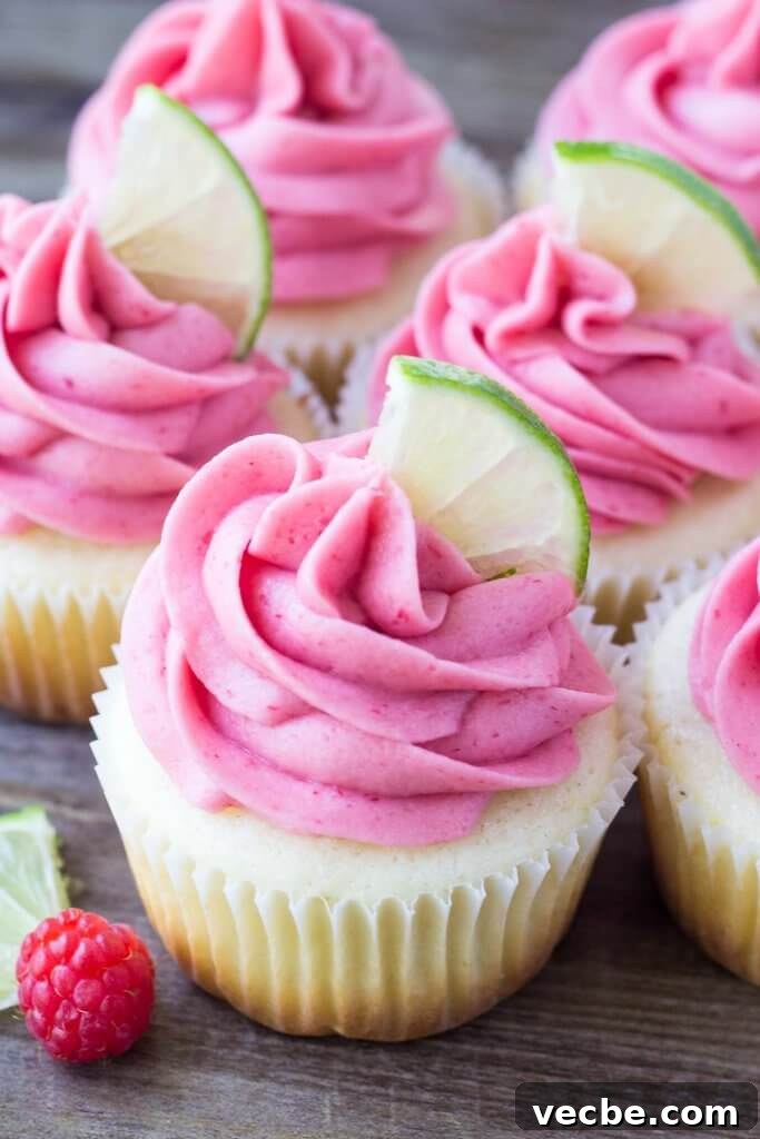 Zesty Lime Cupcakes with Raspberry Buttercream 2 Group of lime cupcakes with raspberry frosting with a lime slice on top.