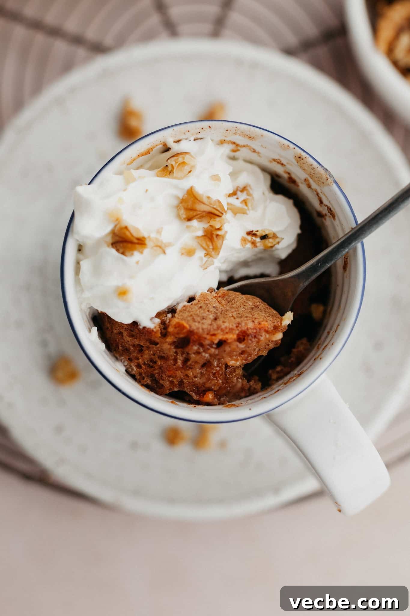 Carrot Mug Cake Recipe 2 An overhead shot of a carrot mug cake topped with whipped cream.