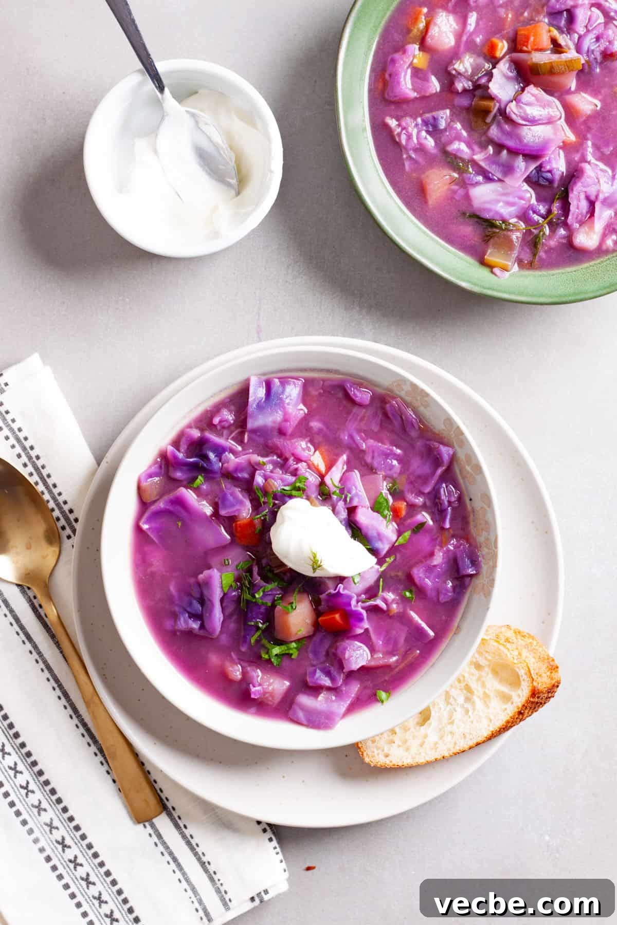 Comforting Red Cabbage Soup Recipe 2 A couple bowls of red cabbage soup topped with fresh herbs and sour cream.