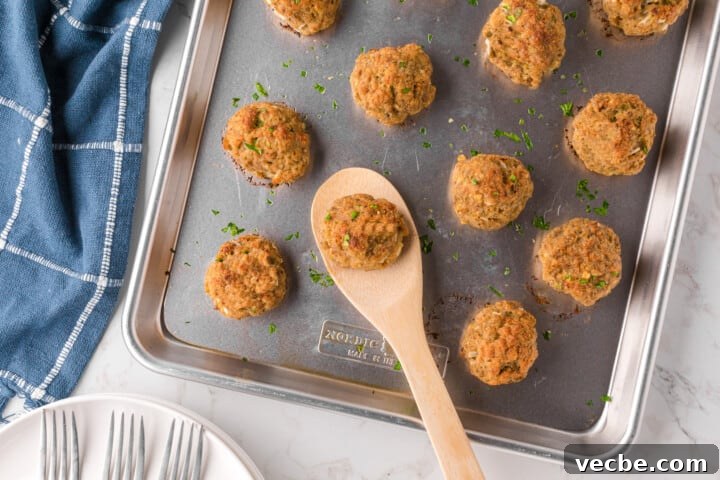 Baked Turkey Meatballs in Marinara Sauce 3 turkey meatballs on baking sheet being served with wooden spoon.