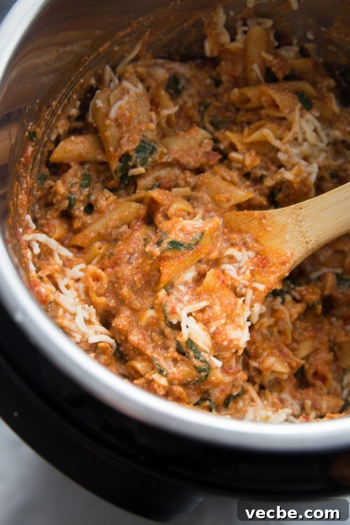 Instant Pot Baked Ziti Recipe 5 Instant Pot cooked baked ziti with melty cheese being stirred with a wooden spoon