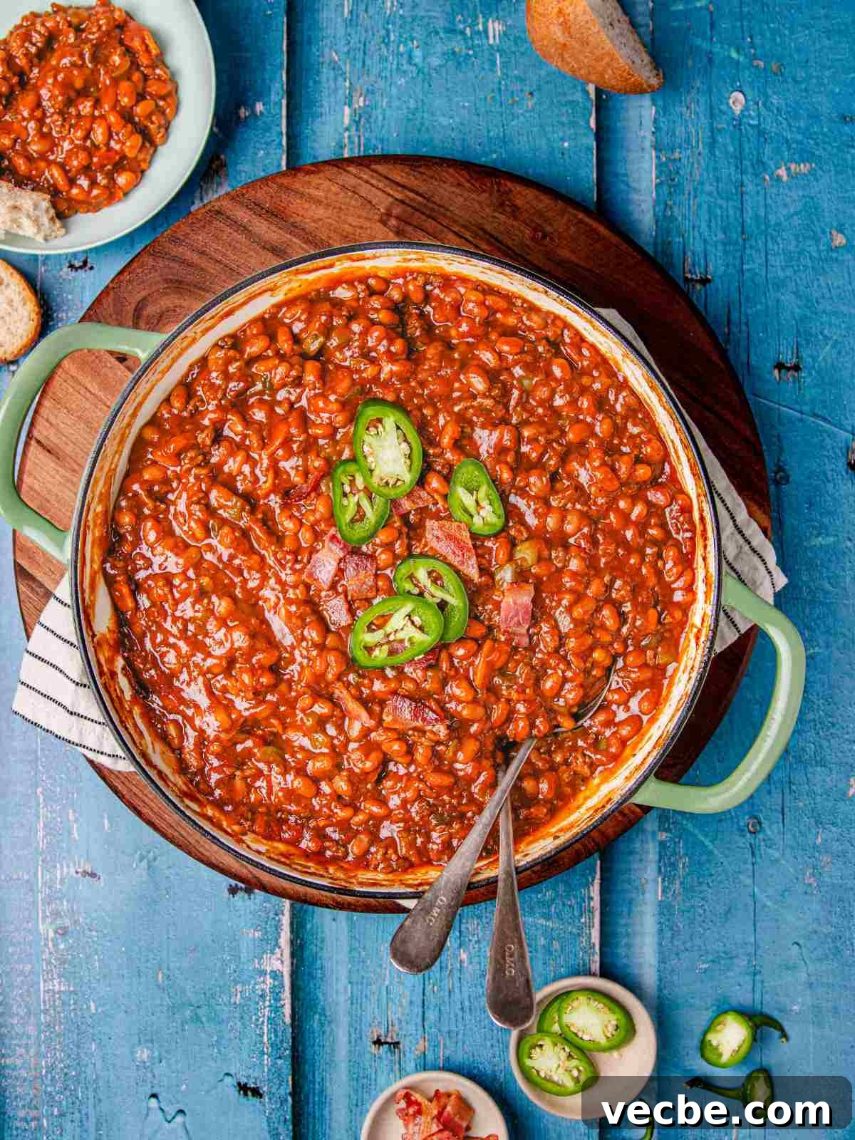 One-Pot Baked Beans with Ground Beef Recipe 2 bean and beef in a cast iron pan with bread on a flat surface.