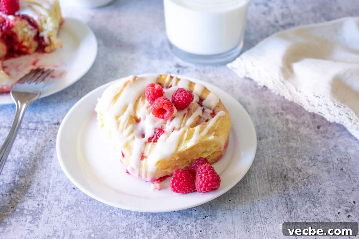 Homemade Raspberry Sweet Rolls Recipe 7 A sweet roll with raspberries on a plate.