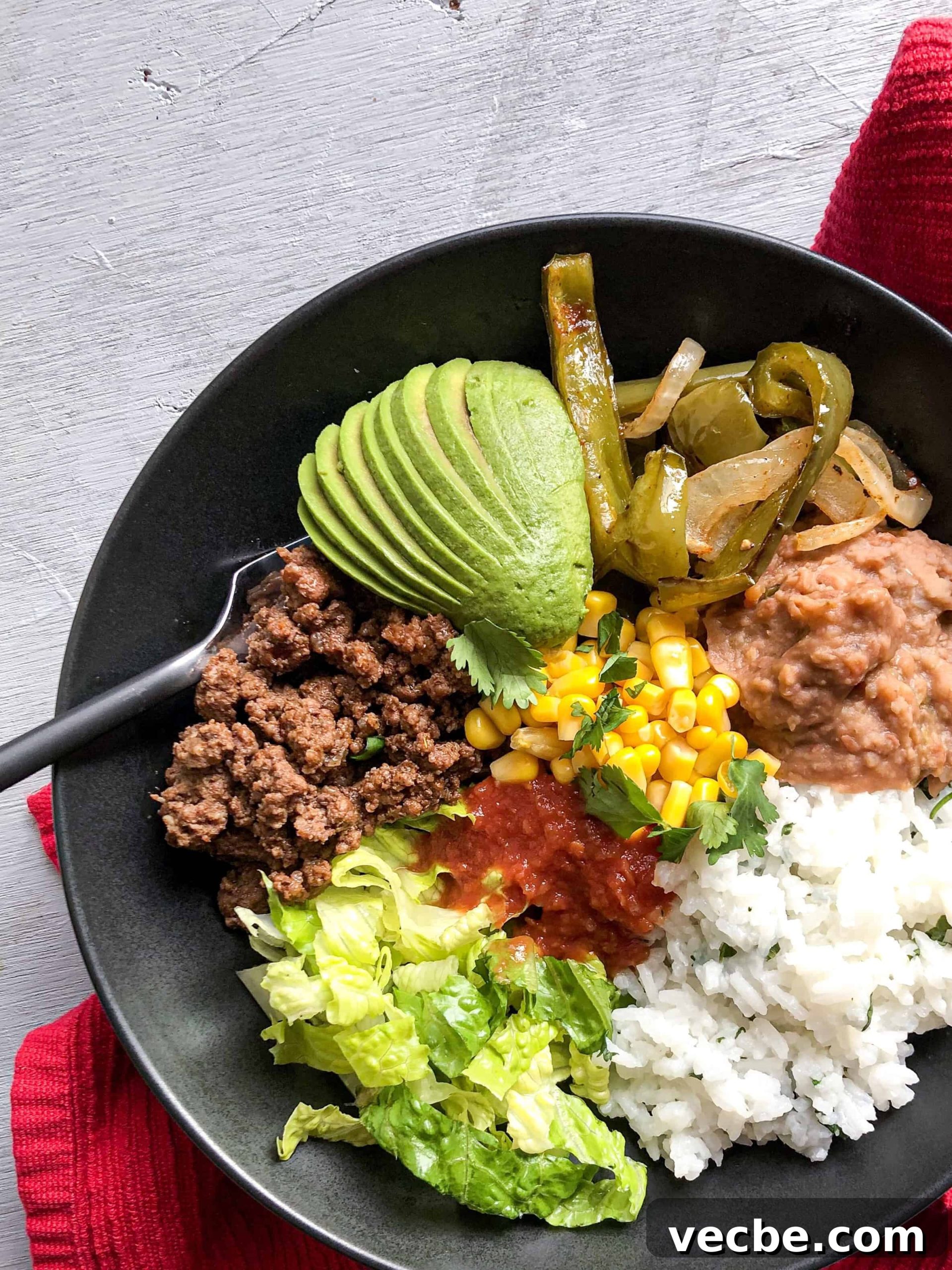 Gluten-Free Burrito Bowls with Rice and Beans 4 A burrito bowl with lots of veggies next to a red towel