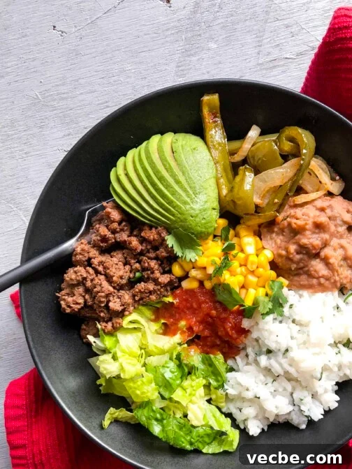 A burrito bowl with lots of veggies next to a red towel