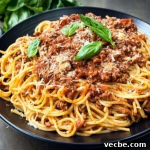 Instant Pot Spaghetti Bolognese Recipe 7 plated spaghetti garnished with basil and parmesan cheese.