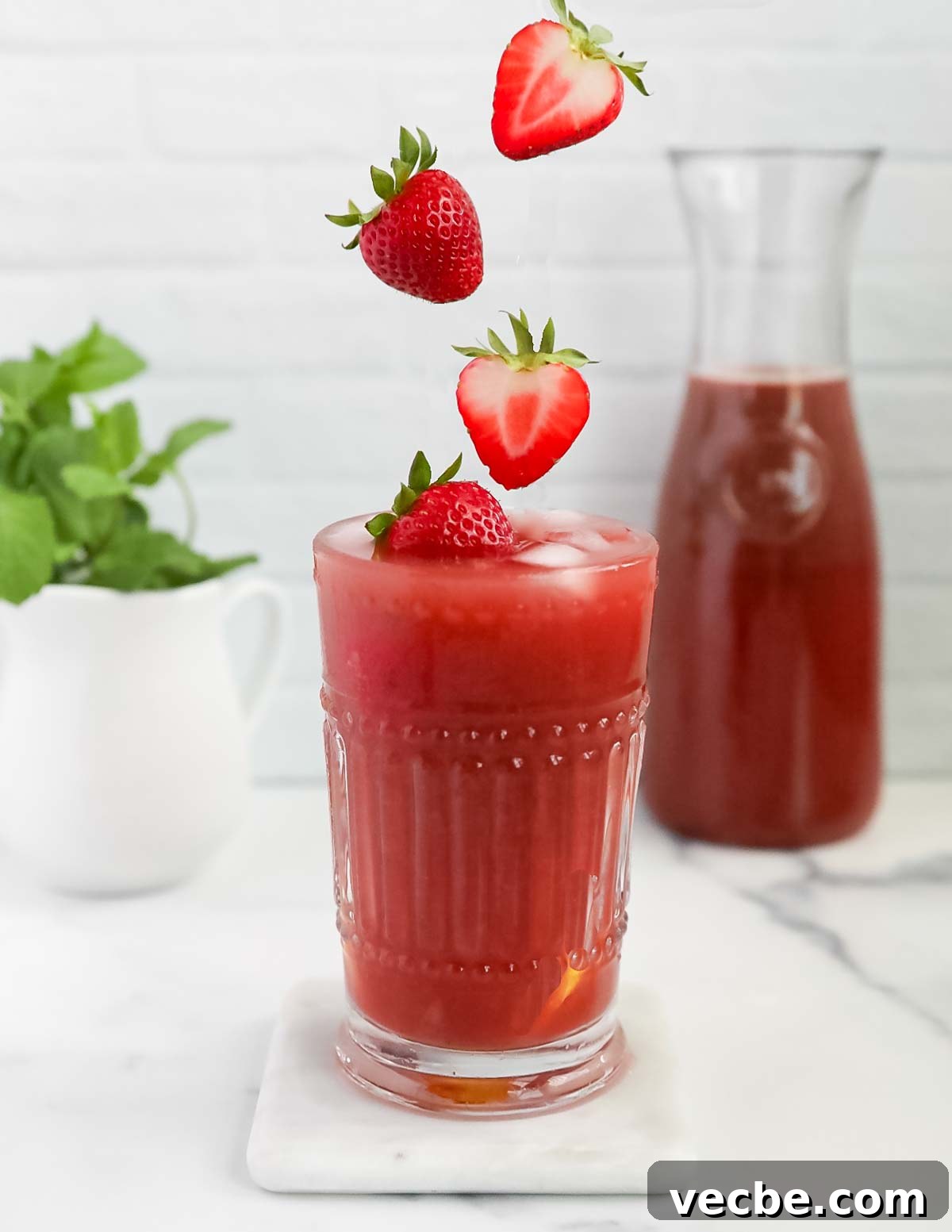 Strawberry Acai Lemonade Recipe 2 A picture of pink lemonade with strawberries falling into the glass