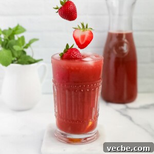 Strawberry Acai Lemonade Recipe 7 Three strawberries falling into a glass filled with pink lemonade