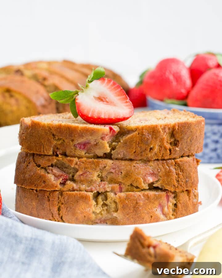 A plate of strawberry banana bread with a strawberry on top.